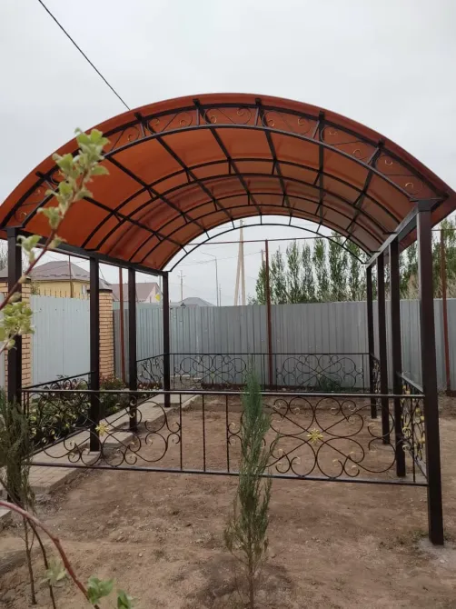 Металл құрылымымен және мөлдір шатыры бар арқады навес қоршалған бақта