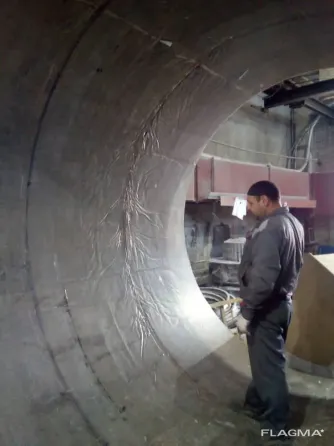 Крупный промышленный цилиндр, висячий на подвеске в производственном помещении