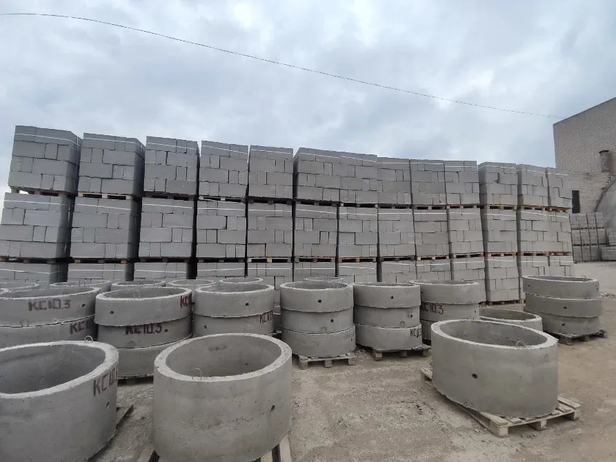 Куча бетонных блоков и колец на стройплощадке под облачным небом