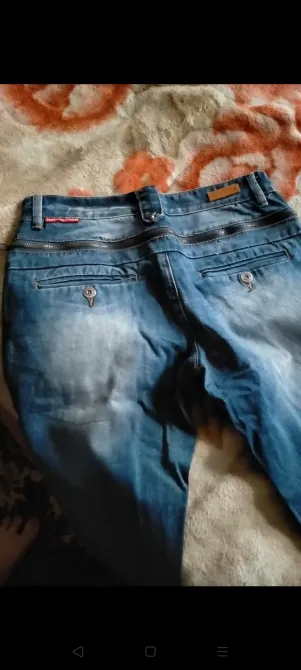 Гүлді өрнекті жамылғының фонында джинстарының артқы бөлігі