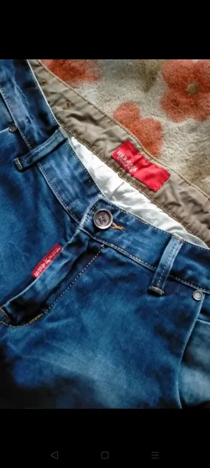 Гүлді өрнекті жамылғының фонында джинсы жақын жоспар.