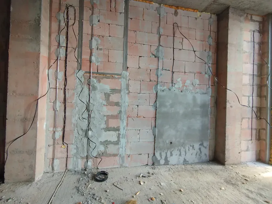 Стена с электрической проводкой в процессе отделки, видимые провода и бетонные блоки