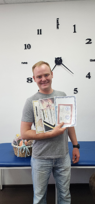 Человек стоит с сертификатами в руках на фоне настенных часов