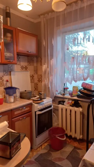 Кухня с кухонной утварью и окном, через которое виден двор