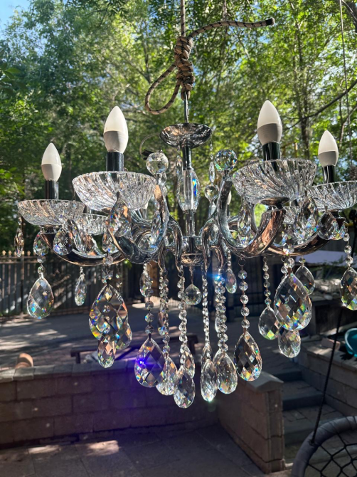 Жасыл фондағы жарық тамшыларымен хрусталды люстра