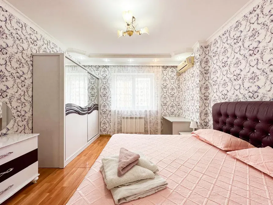 Спальня с кроватью и старыми обоями, уютным освещением и окнами