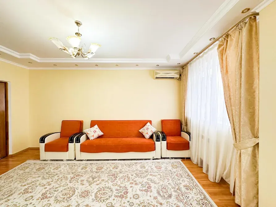 Гостиная с оранжевыми диванами и ковром, окрашенная в теплые тона