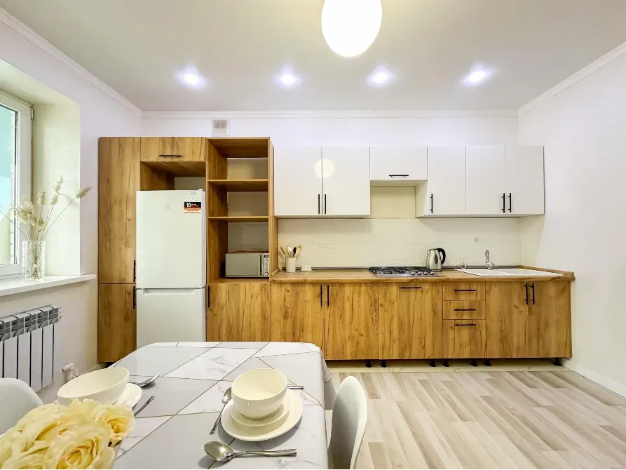 Кухня с белыми и деревянными шкафами, бытовой техникой