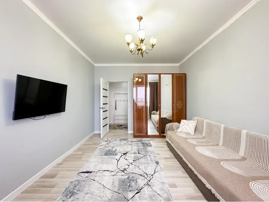 Гостиная с диваном и телевизором, оформленная в светлых тонах