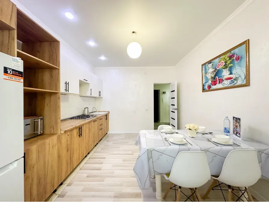 Кухня с деревянными шкафами, столом и стульями, ярким светом