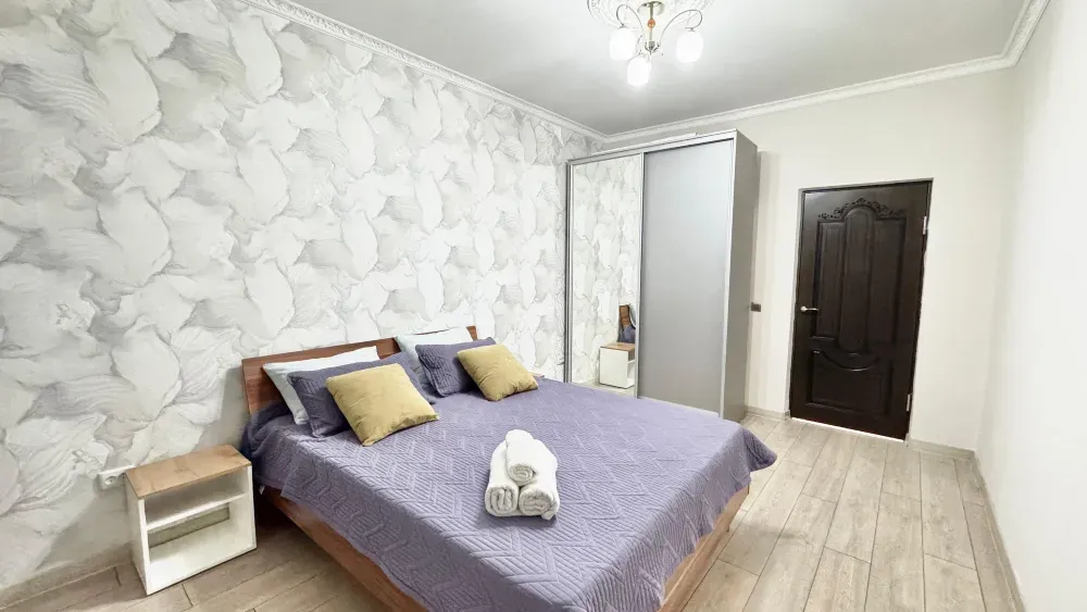 Спальня с матрасом, подушками и шкафом, оформленная в светлых тонах