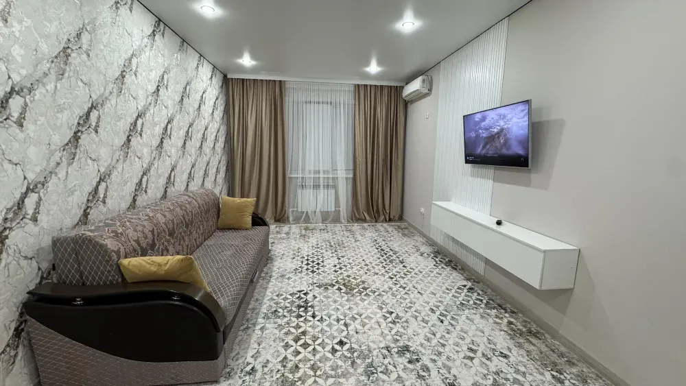 Гостиная с диваном и телевизором на стене, оформленная в современных цветах