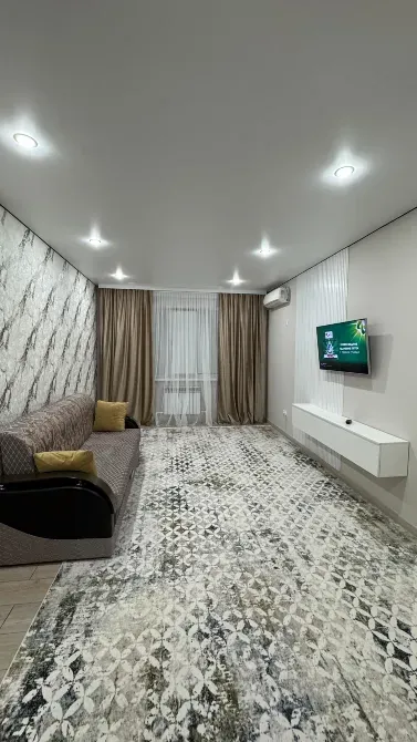 Гостиная с диваном и телевизором, уютное пространство с современным ремонтом