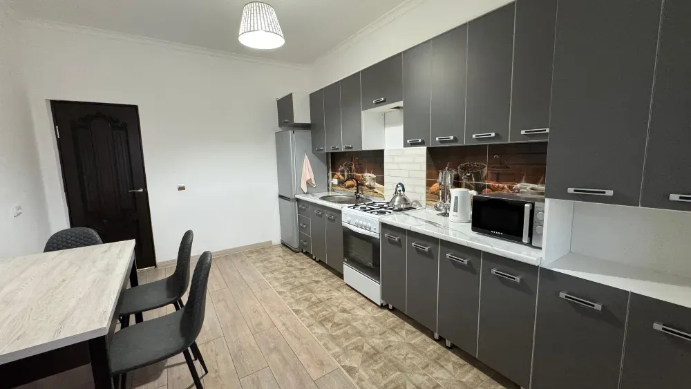 Кухня с современными шкафами, плитой и обеденной зоной