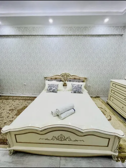 Двуспальная кровать с декоративными подушками на фоне стены с узором