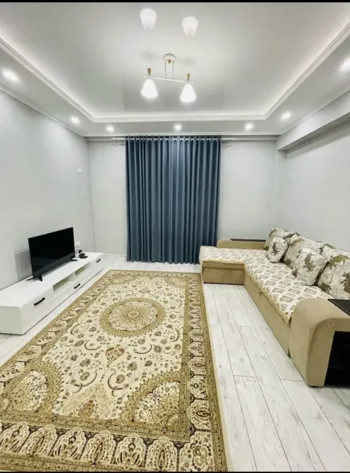 Гостиная с диваном и телевизором на стене, светлый ковер