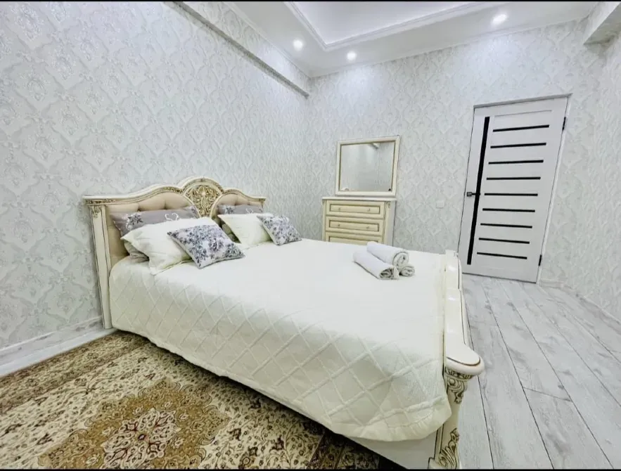 Комната с двуспальной кроватью и декоративными подушками, белые стены и светлый пол