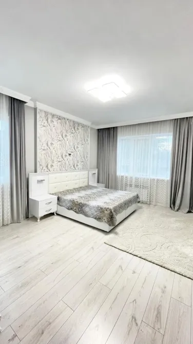 Просторная спальня с светлыми шторами и дизайнерским декором