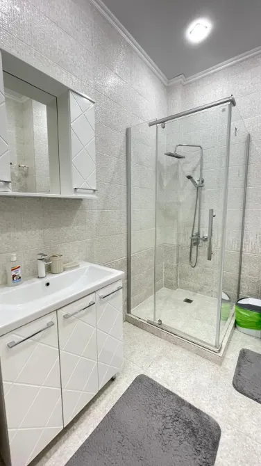 Ванная комната с белой мебелью и стеклянной кабиной