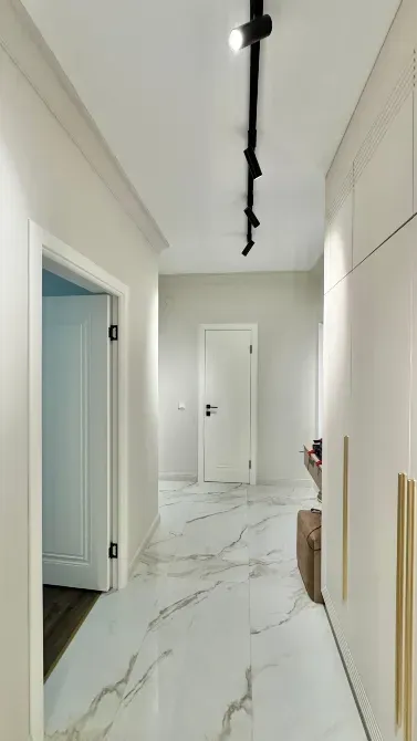 Коридор ақ қабырғалармен және стильді жарықпен