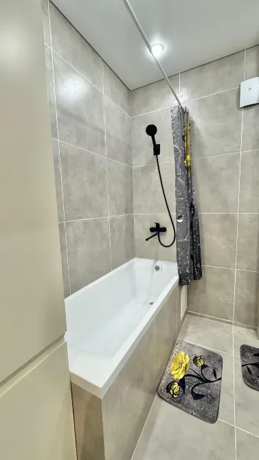 Ванна мен душ жүйесі бар жуынатын бөлмеге көрініс.