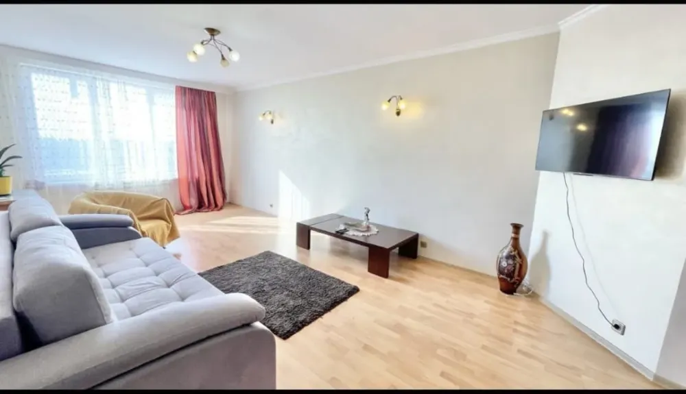 Жарықтандырылған кең қонақ бөлмесі мен теледидар