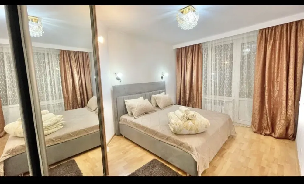 Айна шкафы, төсек және жағымды жарықтандыруы бар ұйықтау бөлмесі