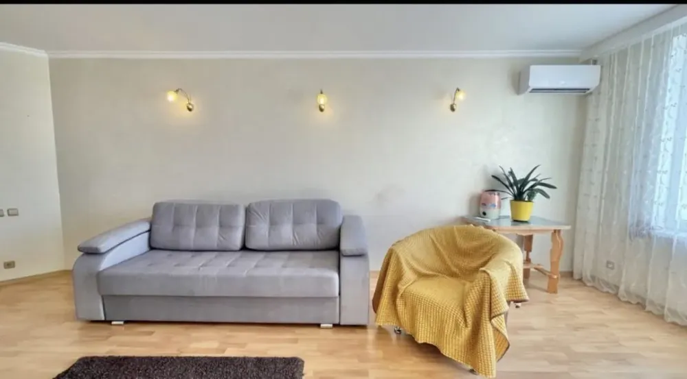 Диван мен үстелде өсімдікпен жайлы қонақ бөлмесі