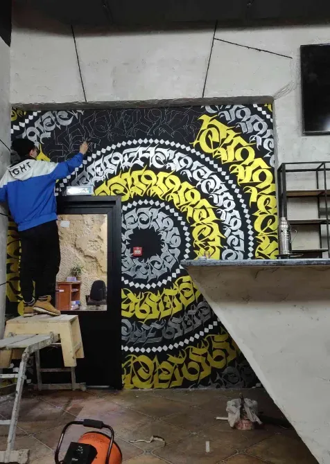 Художник создает черно-желтое граффити на стене