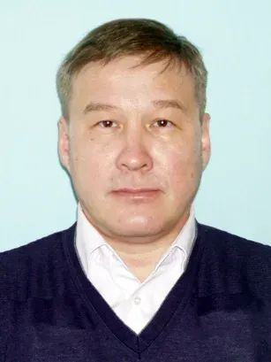 Лицо мужчины на фоне светло-голубой стены, одетого в темный свитер и белую рубашку