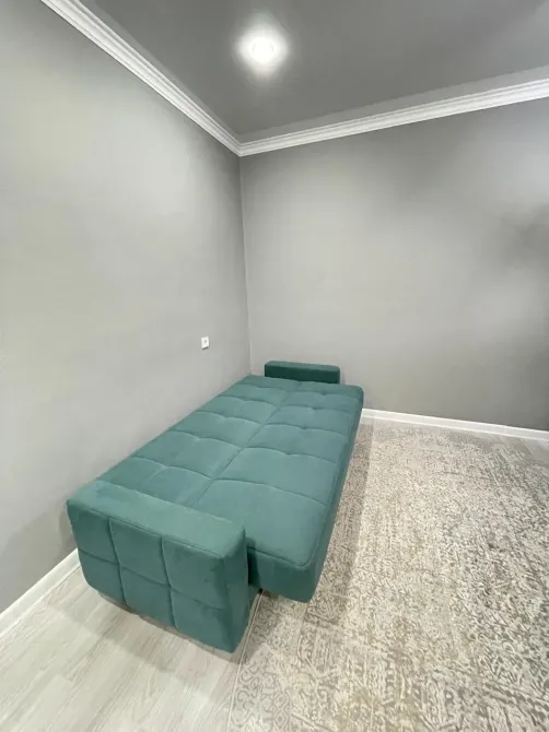 Минималистичная комната с зеленым диваном