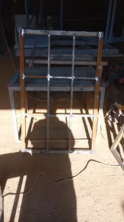 Металлическая рама с горизонтальными перекладинами, сваренная из труб, стоит на земле с теневой подсветкой