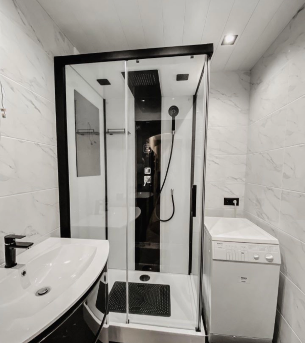 Душевая кабина в белой ванной комнате с стиральной машиной