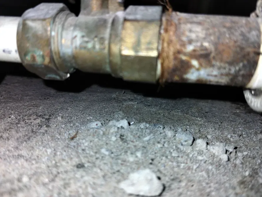 Ескі су құбыры арматурасы бетонды бетте жар cracksтары мен коррозия іздерімен.