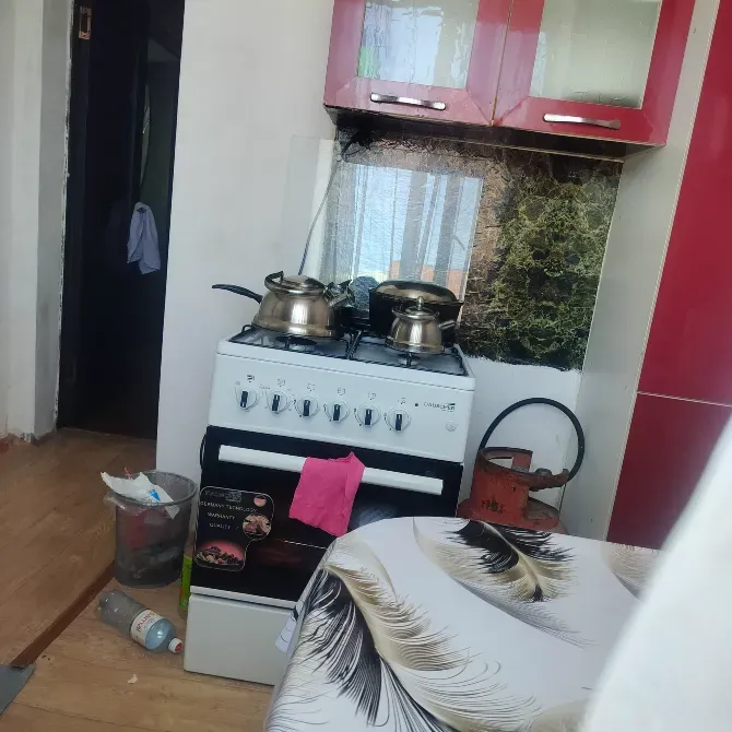 Кухня с газовой плитой и кухонной утварью, окна с солнечным светом