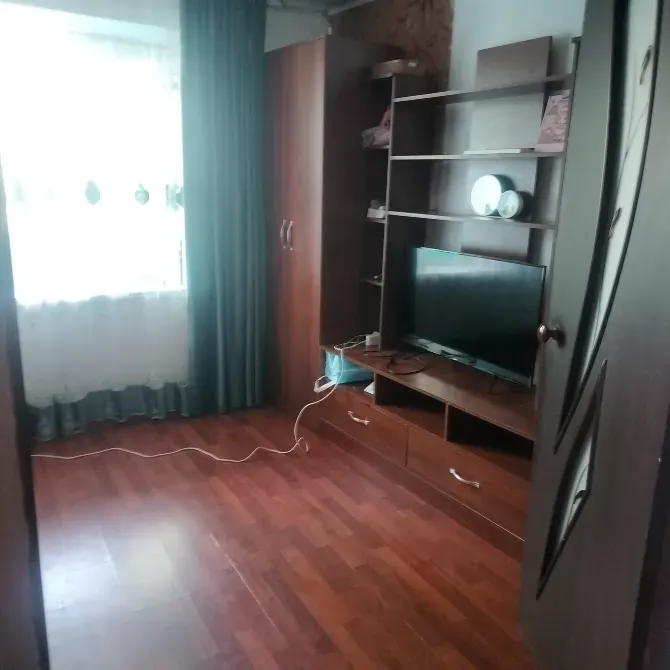 Уютная комната с телевизором и мебелью, паркетный пол, зелёные занавески