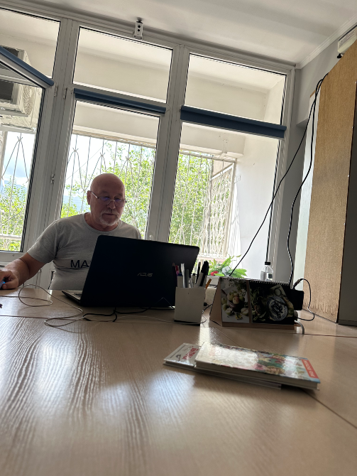 Офисте үстелде жұмыс істеп отырған компьютердегі ер адам