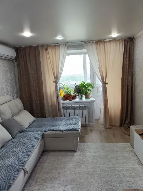 Диван мен терезедегі өсімдіктері бар қонақ бөлме