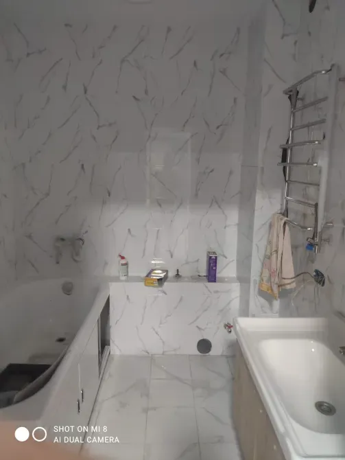 Ақ мәрмәрмен безендірілген ванна бөлмесі мен ванна