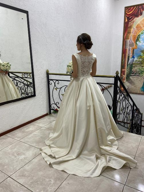 Невеста в свадебном платье с длинной юбкой, стоящая на лестнице, видно, как платье спускается по ступенькам