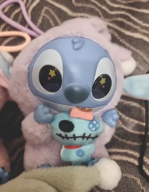 Ститч күлгін костюммен, черепті ойыншықты ұстап, оған құштарлықпен қарайды