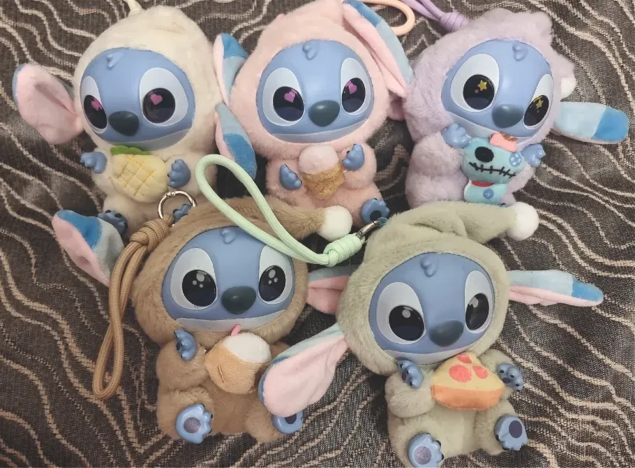 Дисней Ститч персонажымен жұмсақ ойыншықтар түрлі түстер мен позаларда, әртүрлі заттарды ұстап тұрады; аксессуарлар коллекциясы