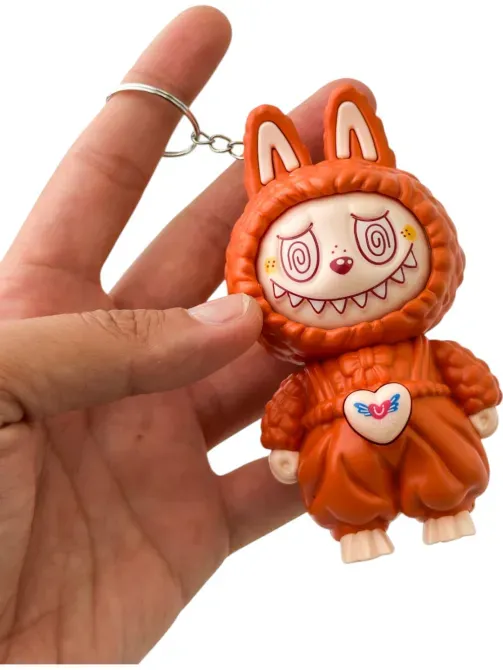 Оранжевая игрушка, которую держит в руке, с хмурым лицом и капюшоном