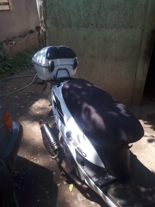 Қара орындықпен және артқы жағында ақ кофрмен мотоцикл бейресми жерлерде