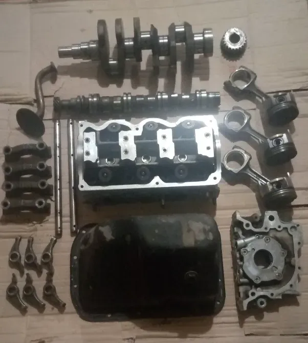 Автомобиль қозғалтқышының бөлшектері, соның ішінде коленчатый вал, распредвал, поршеньдер және басқа компоненттер картонда.