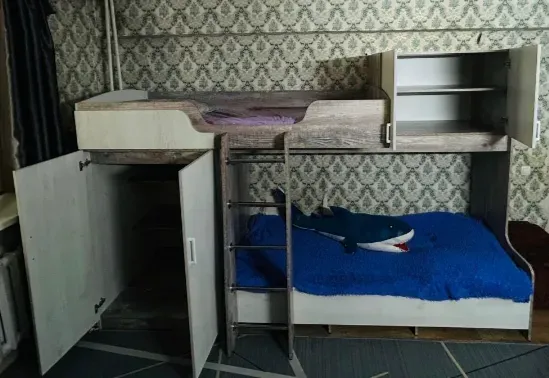 Детская двухъярусная кровать с мягким синим покрывалом и игрушечной акулой