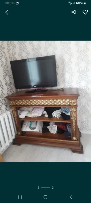 Деревянная тумба с телевизором и полками, на которых лежат вещи