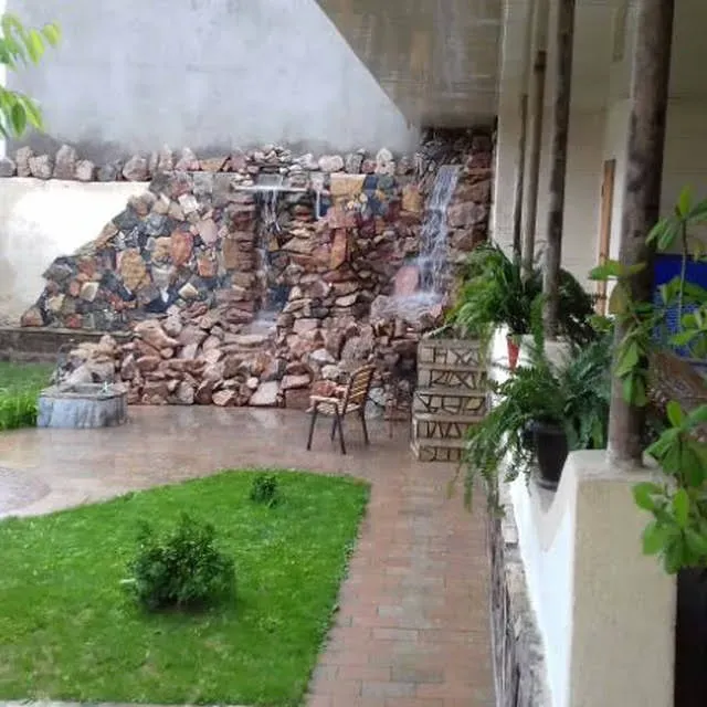 Сад с каменной стеной и водопадом, рядом с креслом для отдыха