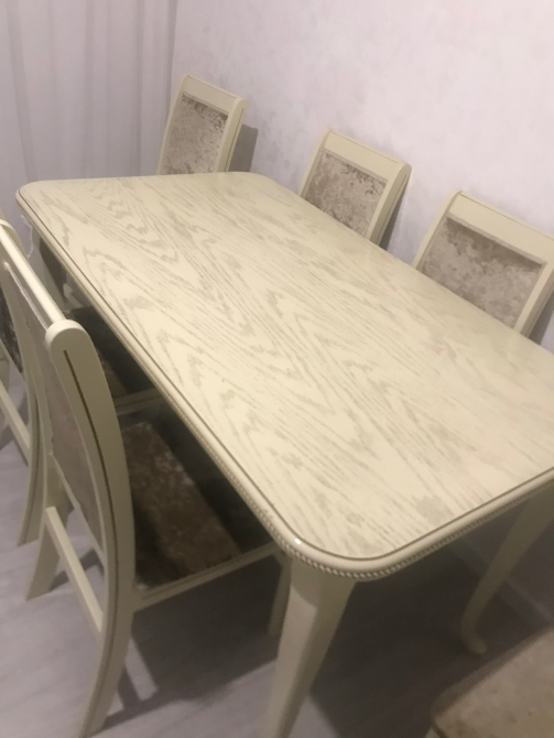 Стол с деревянной текстурой и мягкими сиденьями стульев, расположенный в светлом интерьере