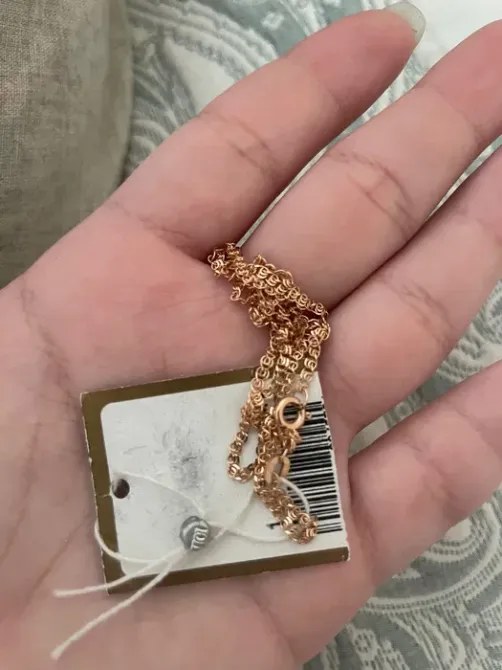 Цепочка из розового золота на руке с ценником и штрих-кодом